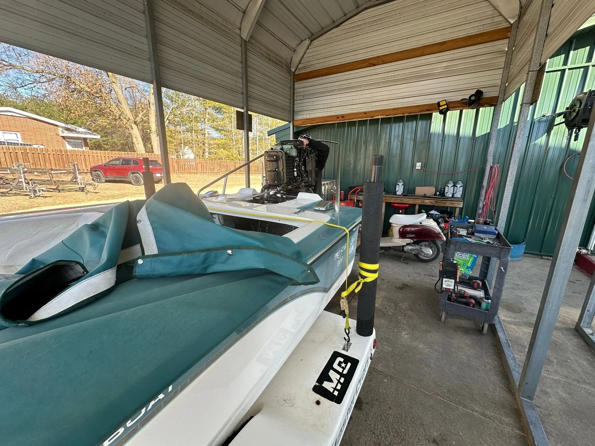Green and white personal watercraft in a covered storage area with tools and equipment nearby