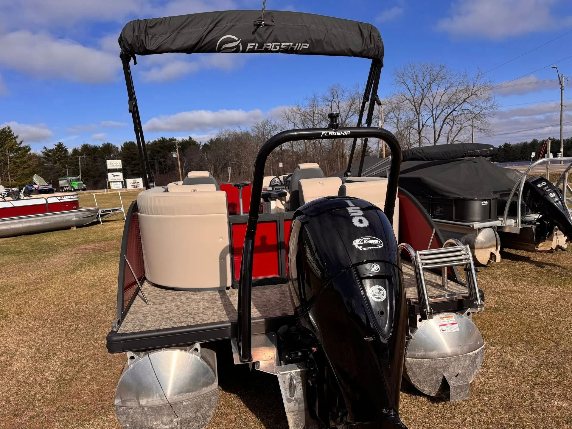 Small boat with black motor and canopy on a trailer in an outdoor lot