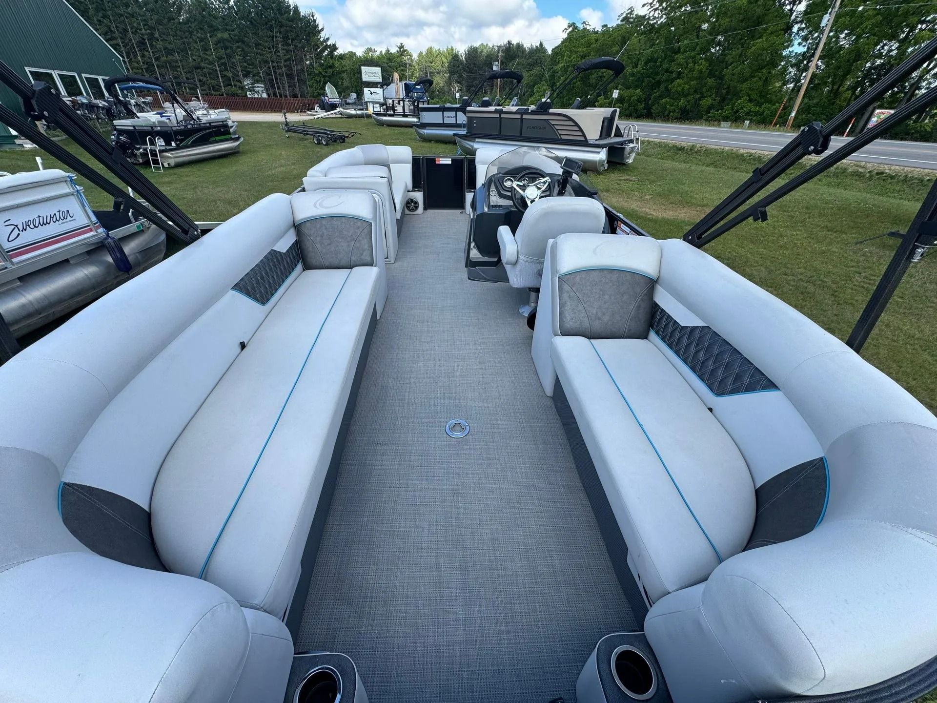 Boat interior with white-and-gray bench seating and a carpeted deck, viewed from the rear toward the bow.