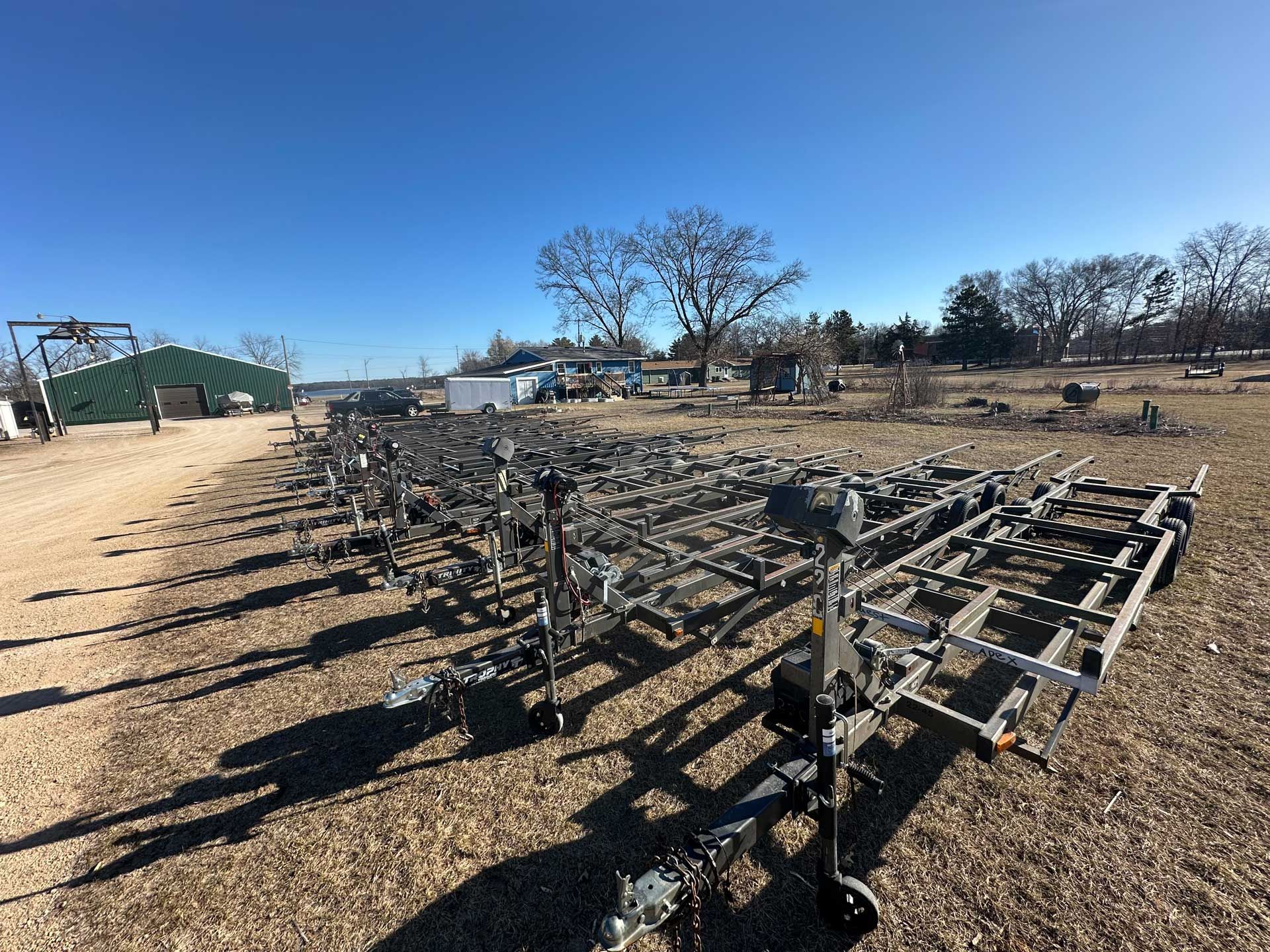 Rows of boat trailers in a dry field under a clear blue sky