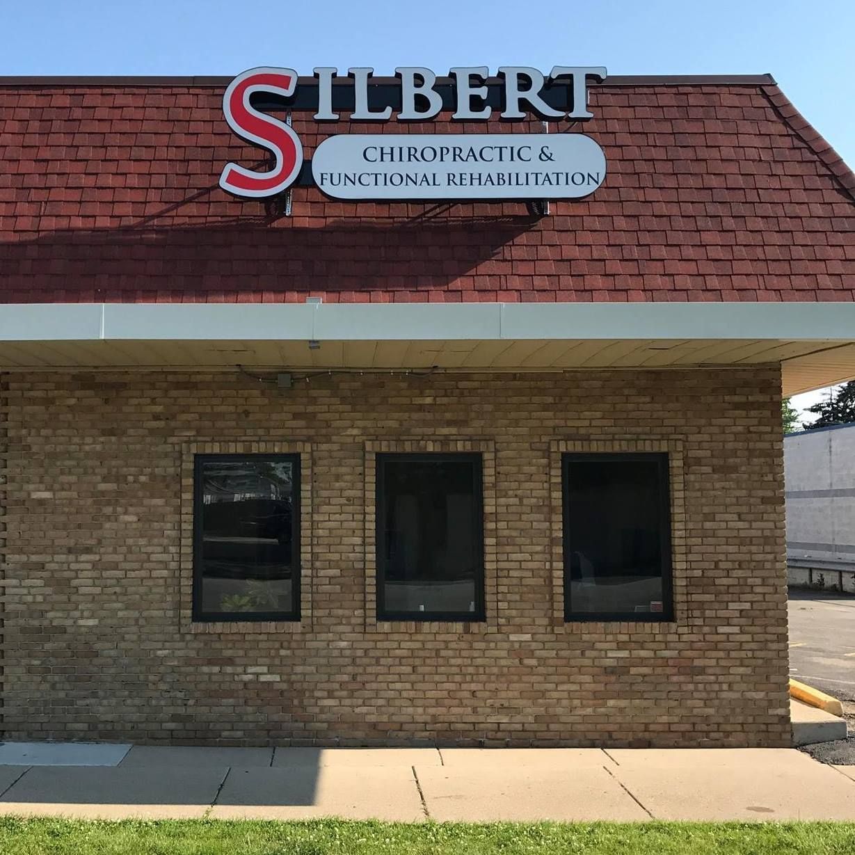 A brick-front building with a sign that reads "SILBERT CHIROPRACTIC & FUNCTIONAL REHABILITATION" under a red roof.
