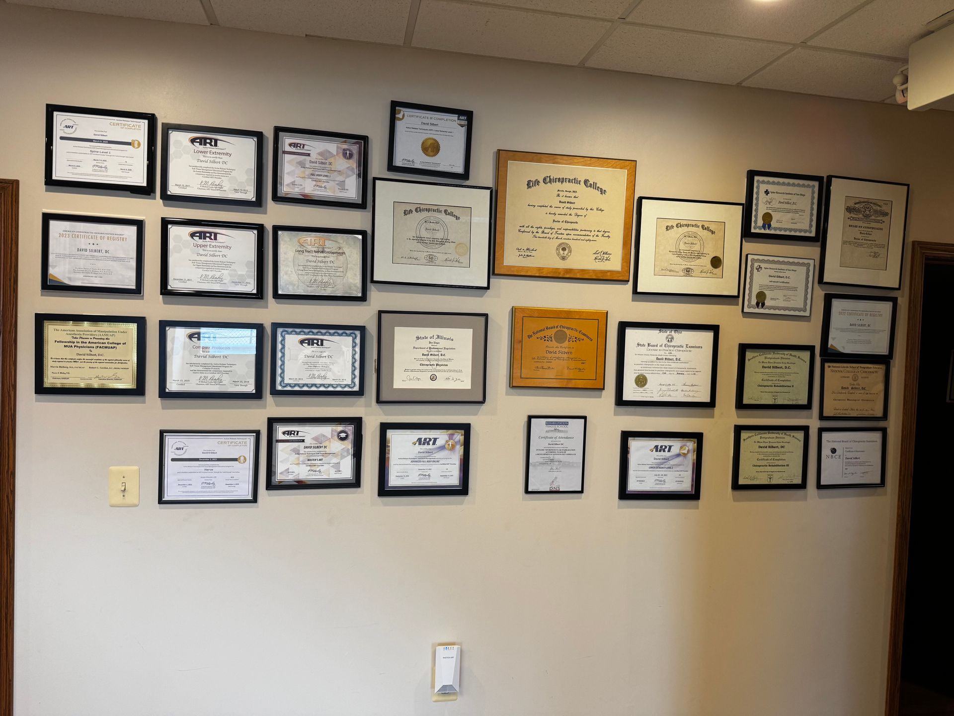 Wall with rows of framed certificates and awards in an office or hallway