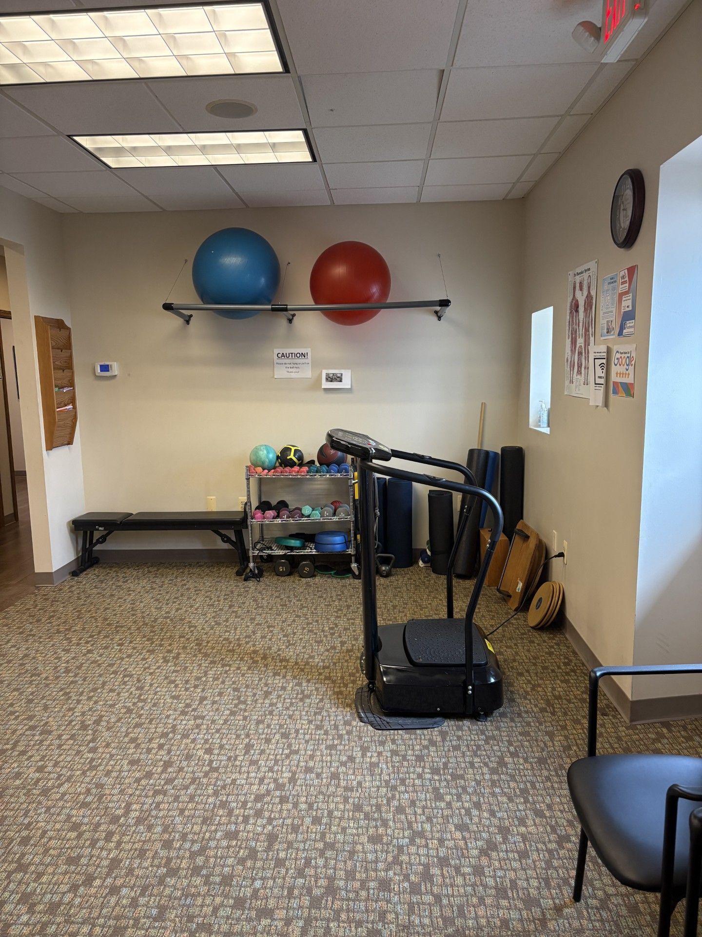 Small gym room with exercise balls on a shelf and a treadmill in the foreground.