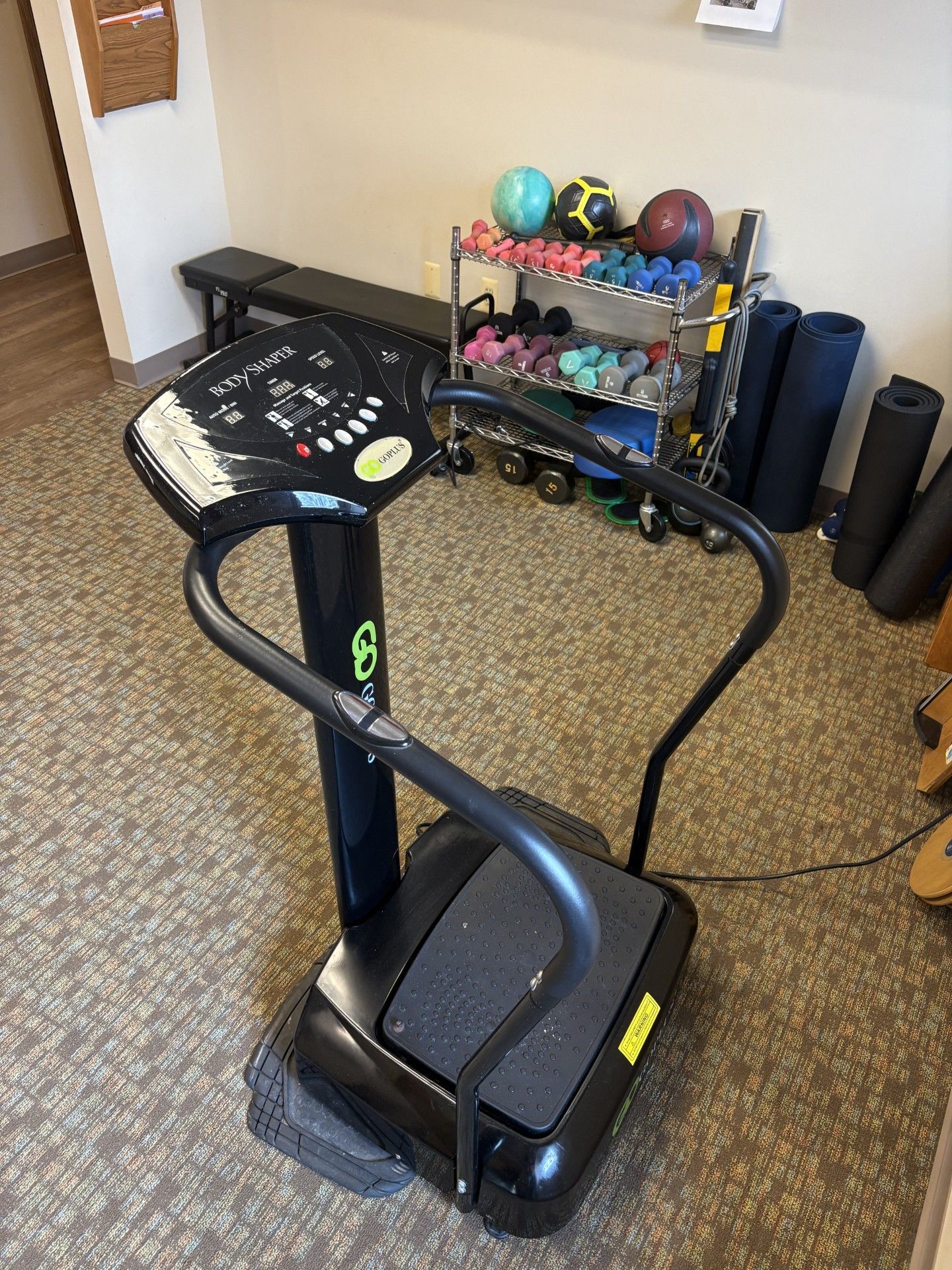 Elliptical exercise machine in a room with shelves of exercise balls and equipment.