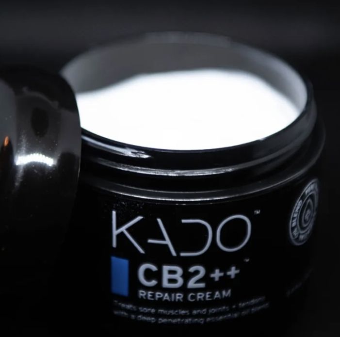 Open jar of KADO CB2++ repair cream on a dark background.