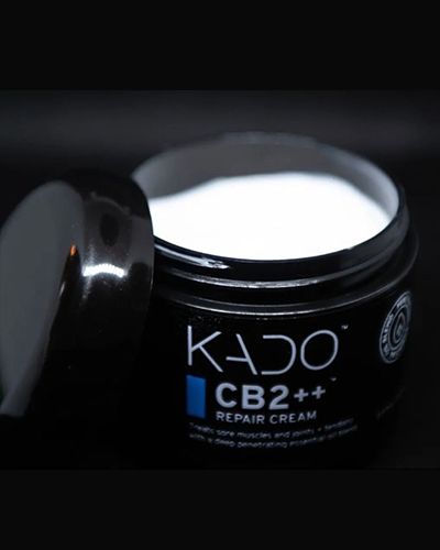 Open jar of KADO CB2++ repair cream with white cream visible on a dark background.