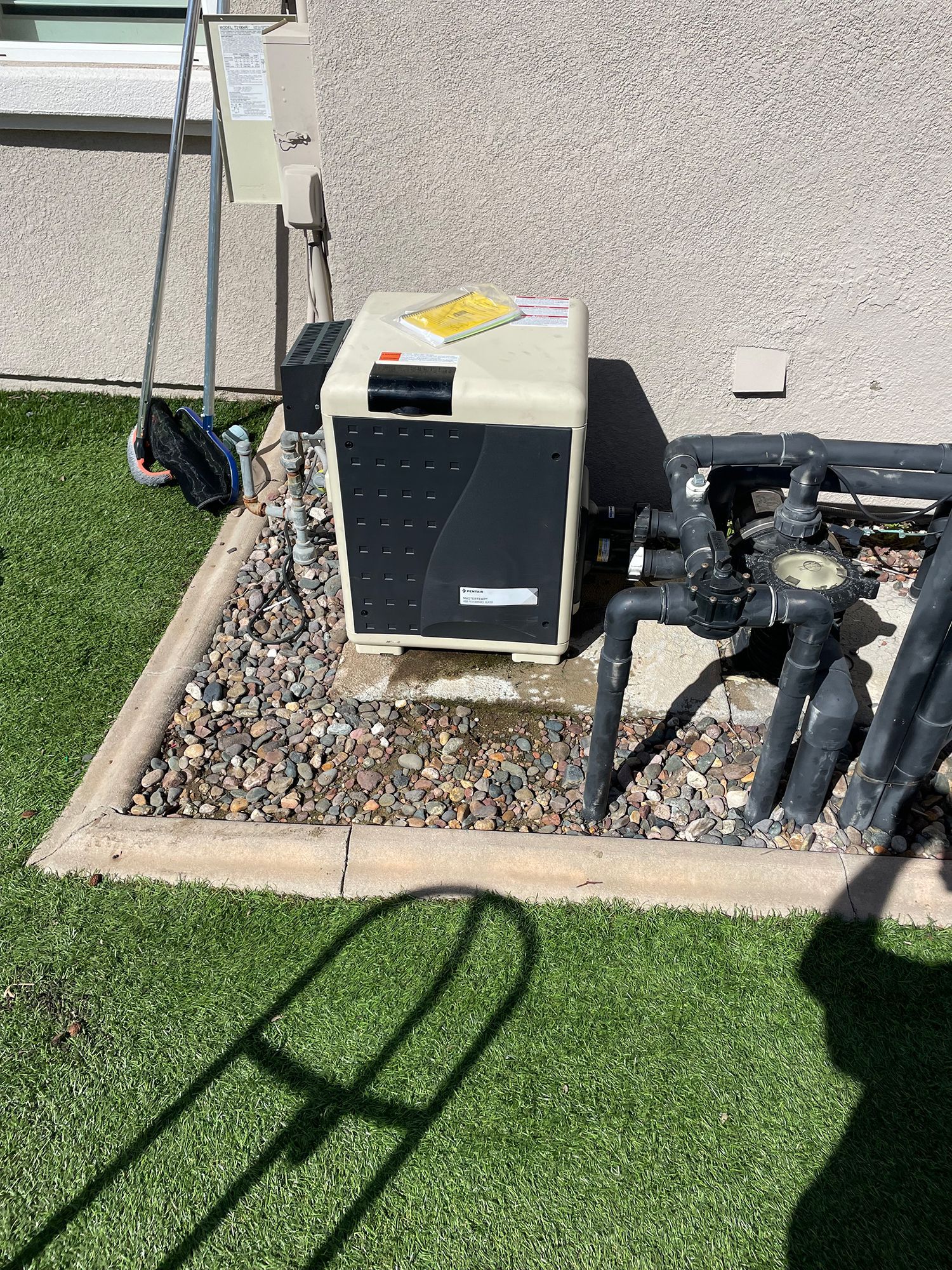 A swimming pool pump is sitting on the side of a house.