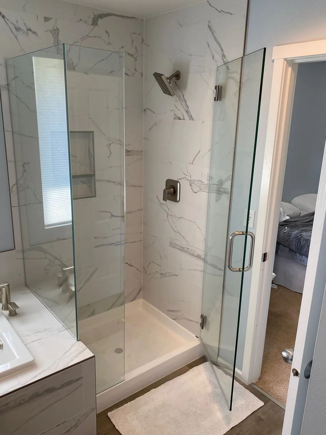 Modern bathroom with a marble-tiled shower and glass doors, and a vanity with a sink.