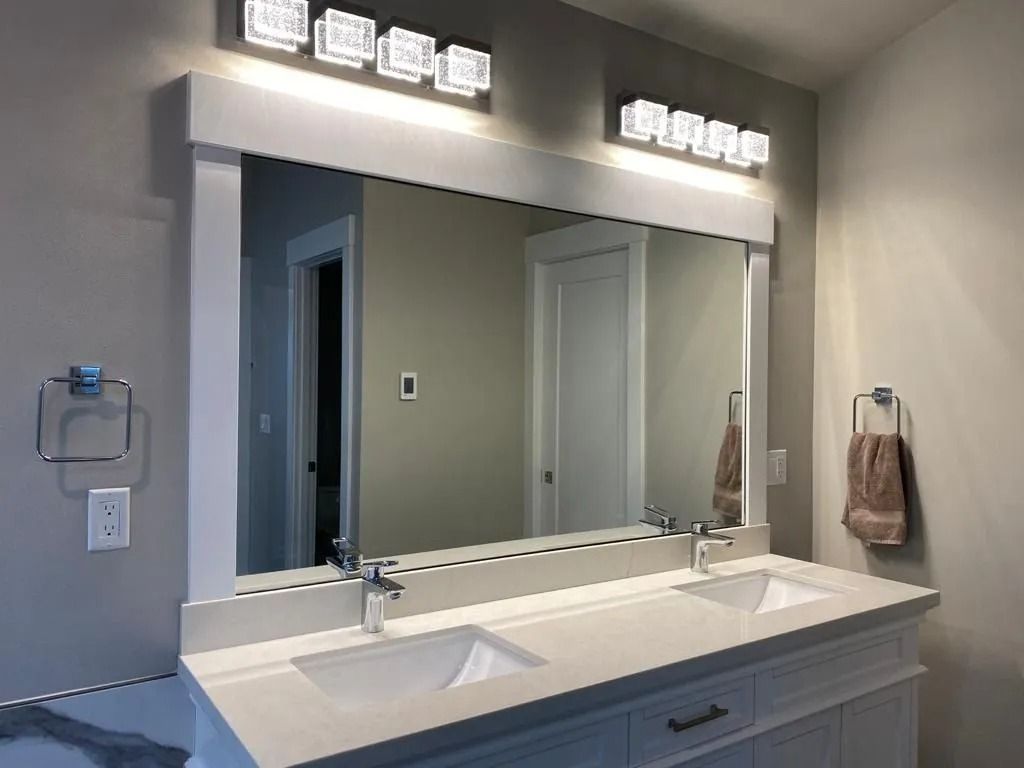 Bathroom with white vanity, double sinks, large mirror, and overhead lighting.