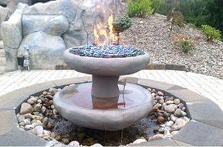 Outdoor fire feature, concrete fountain shape with fire burning above glass beads, water below.