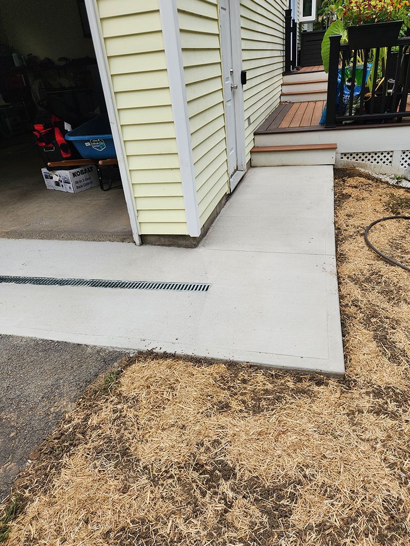 Concrete ramp and pathway leading to a building with a yellow exterior.  Dry grass surrounds the concrete.