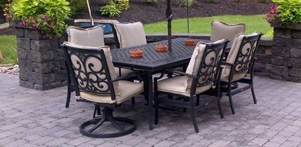 Patio furniture set on a stone patio with potted plants and an umbrella.
