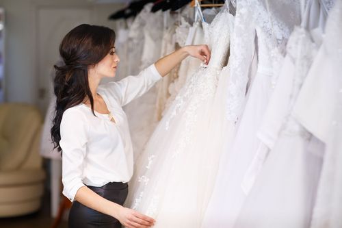 Woman browsing white wedding dresses on a rack in a bridal shop