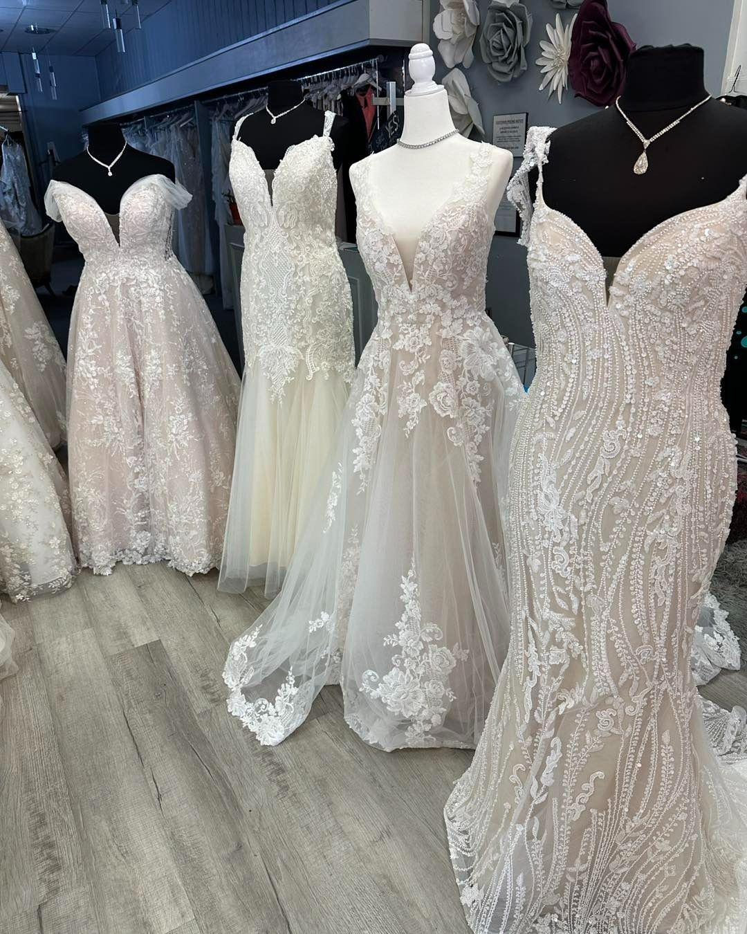 Bridal boutique with several white lace wedding gowns displayed on mannequins