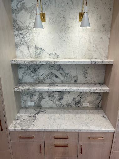 A kitchen with marble countertops, cabinets, and shelves.