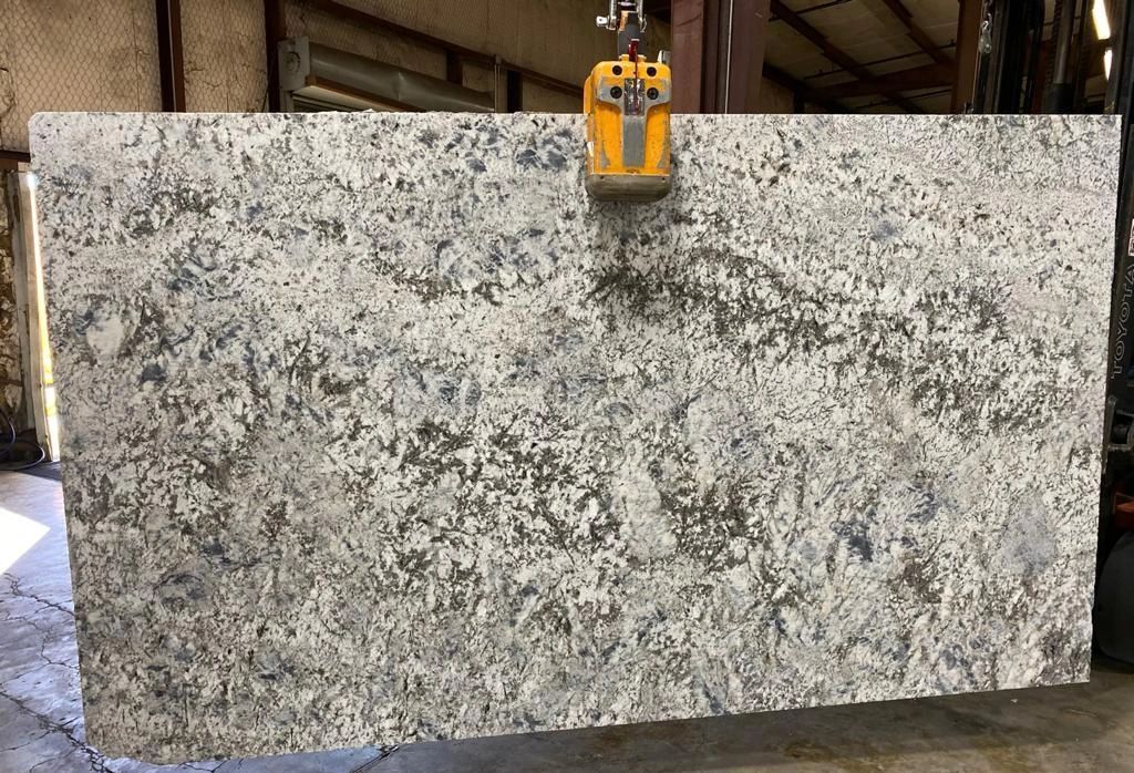 A large slab of granite is being lifted by a crane.