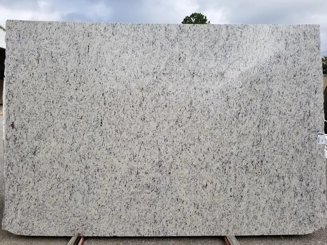 A large white granite slab is sitting on top of a cement floor.