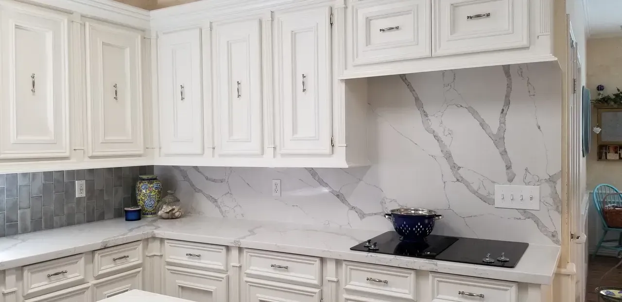 A kitchen with white cabinets and a stove top oven.