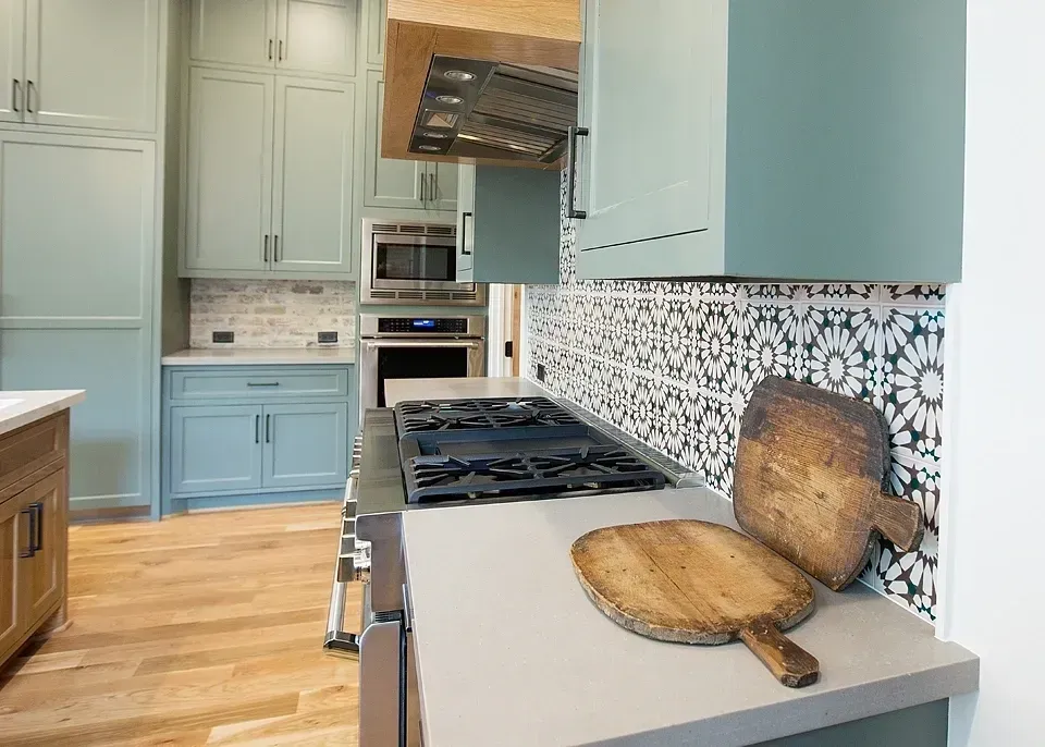 A kitchen with blue cabinets and a wooden cutting board on the counter.