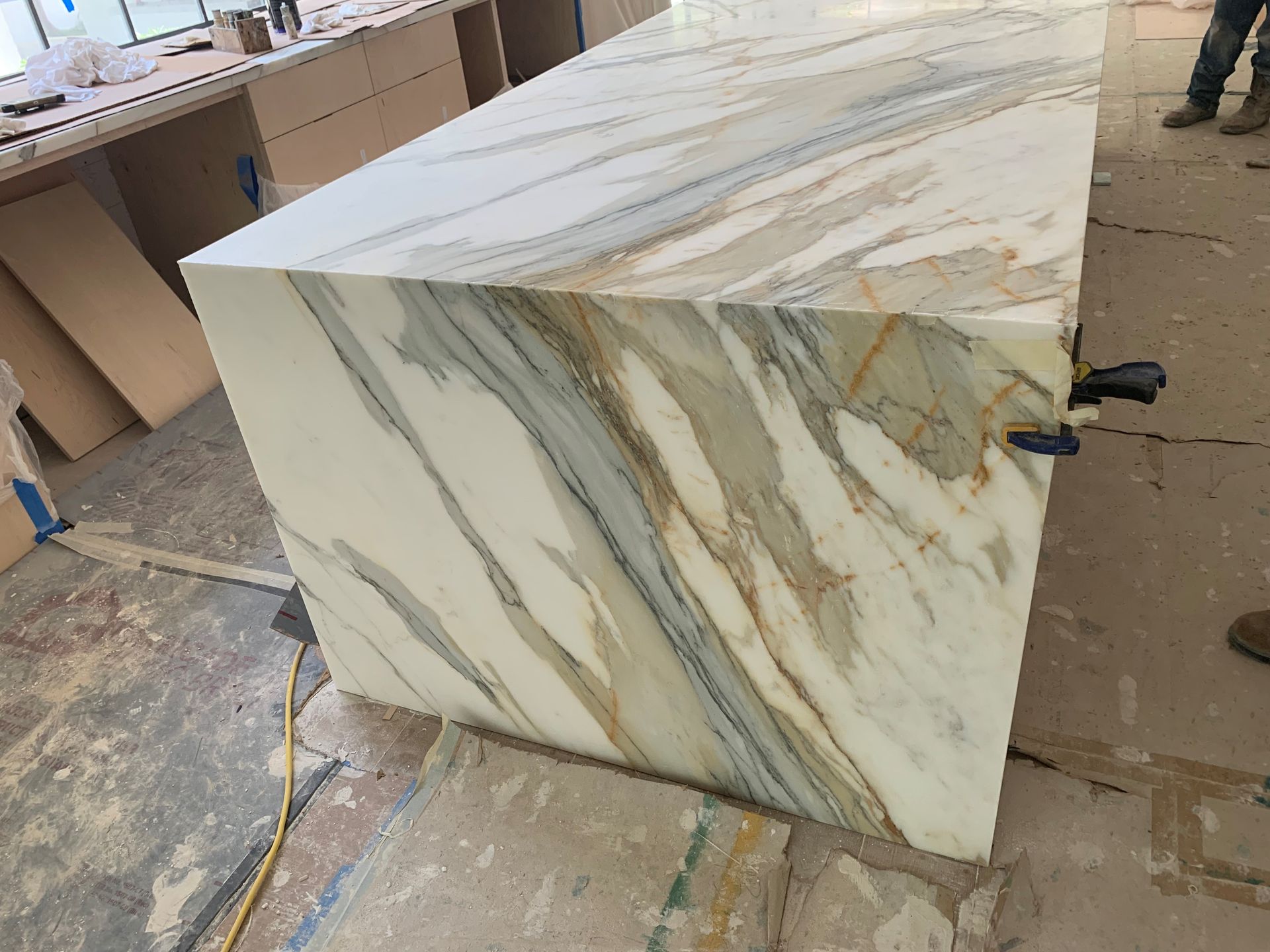 Large marble countertop with gold and blue veining, resting on construction site floor.