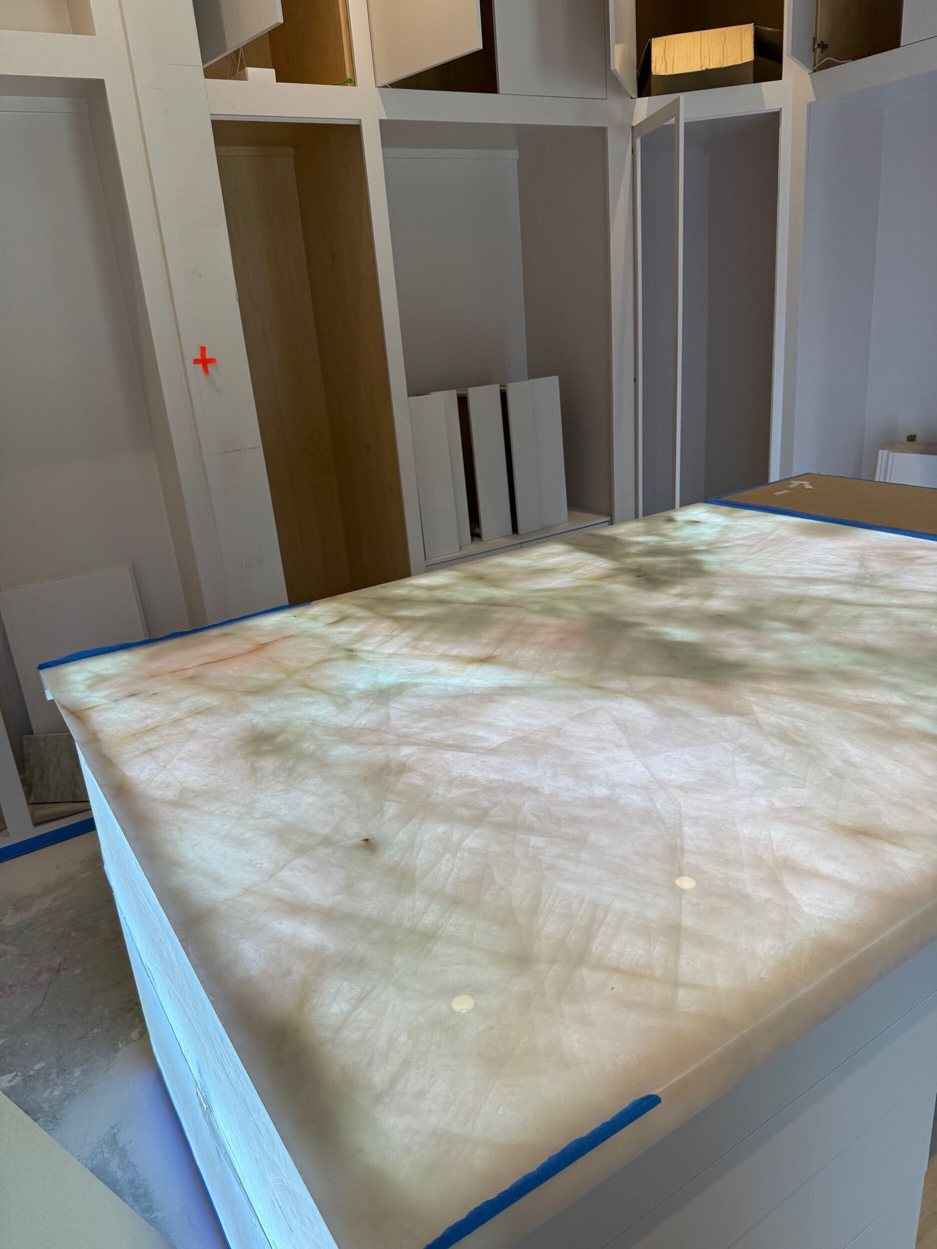 Backlit, translucent countertop in a kitchen renovation with unfinished cabinetry.