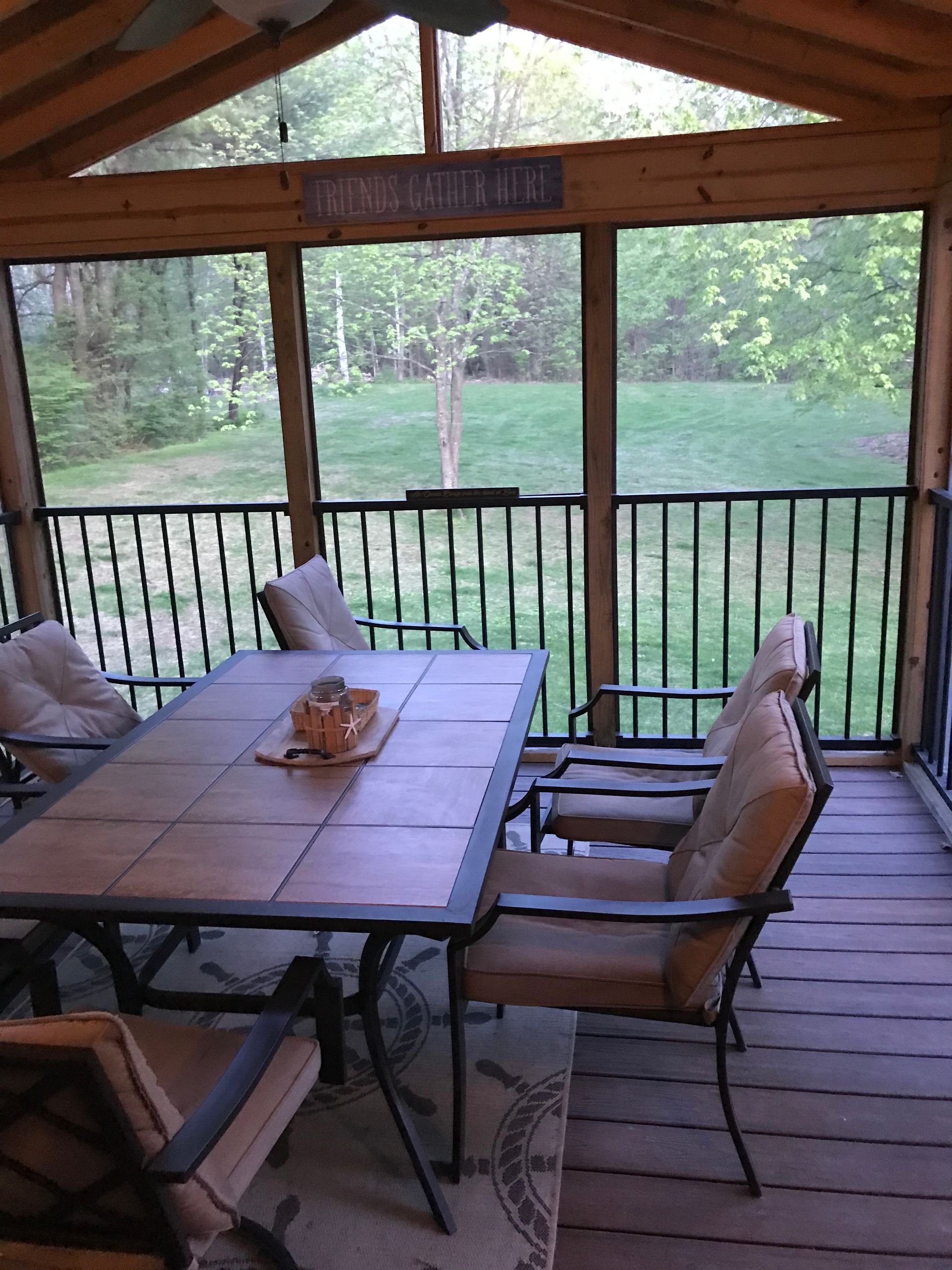Screened-in porch with a table and chairs; backyard view.