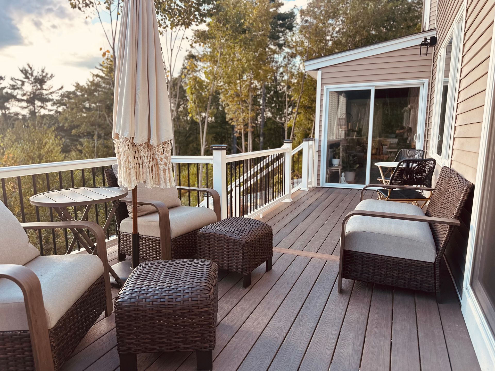Outdoor deck with seating, umbrella, and view of trees.
