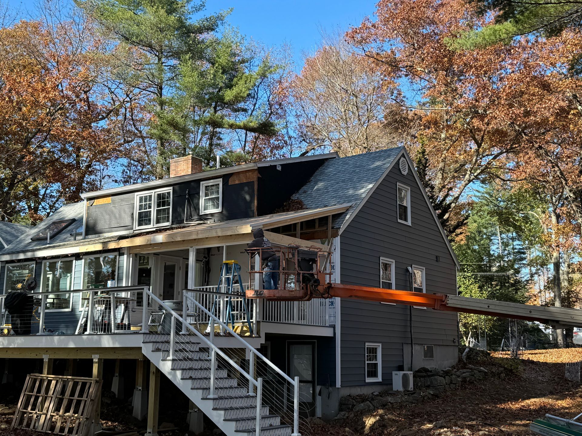 House under renovation with blue siding and construction equipment.