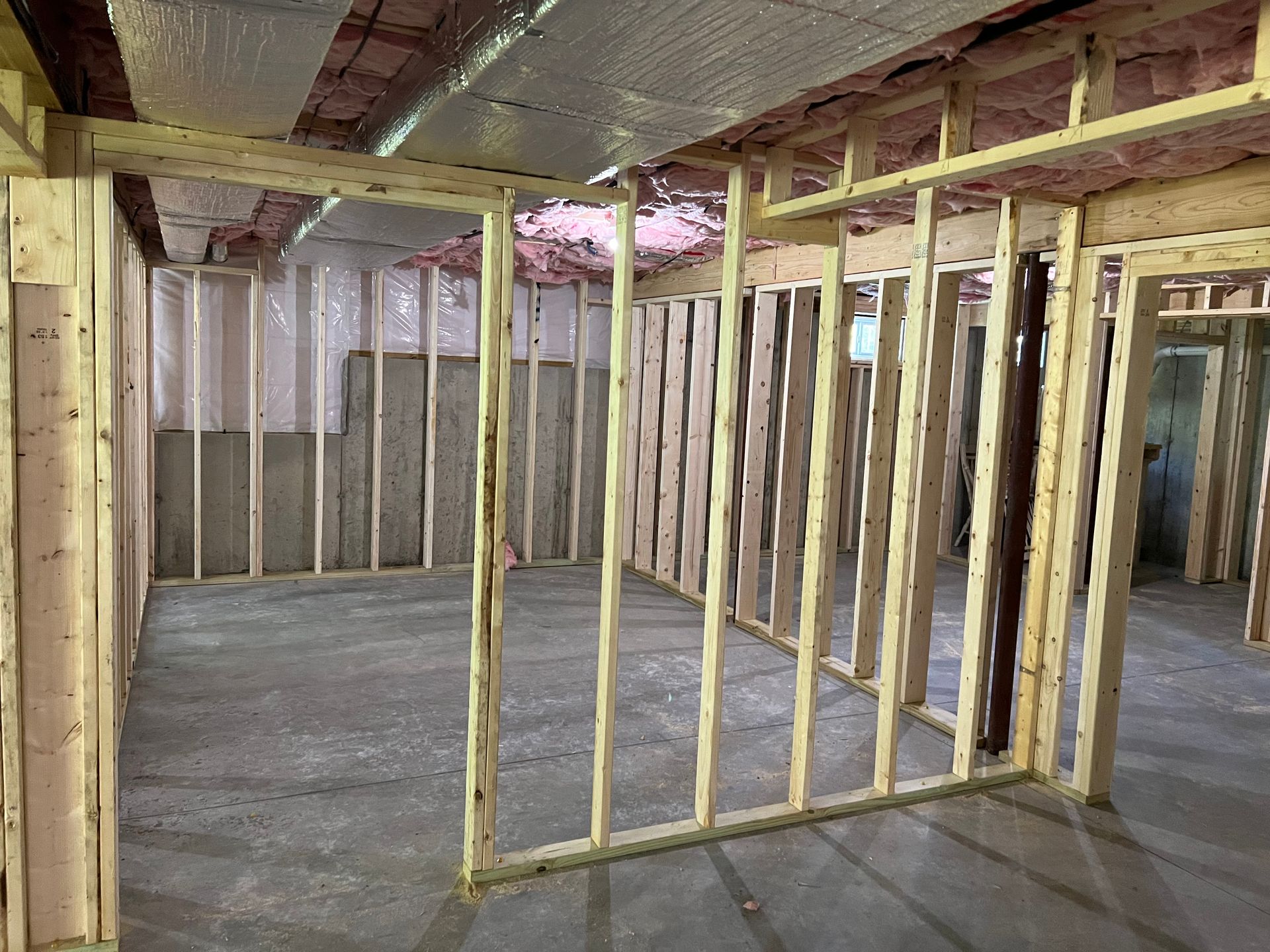 Basement under construction; wooden framing of walls and ceiling; insulation visible.
