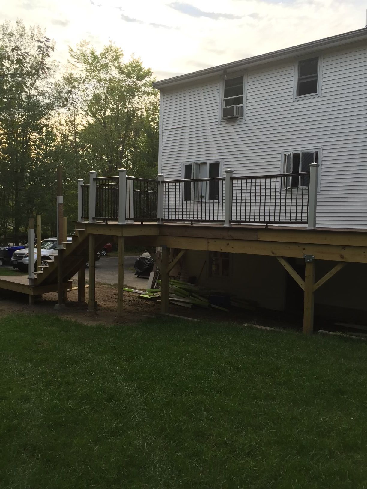 Backyard deck with black railing, attached to a white house, overlooking a grassy yard.