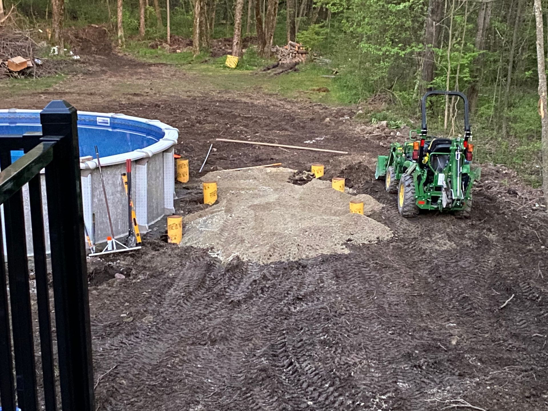 A tractor is preparing a base of gravel next to an above-ground pool.