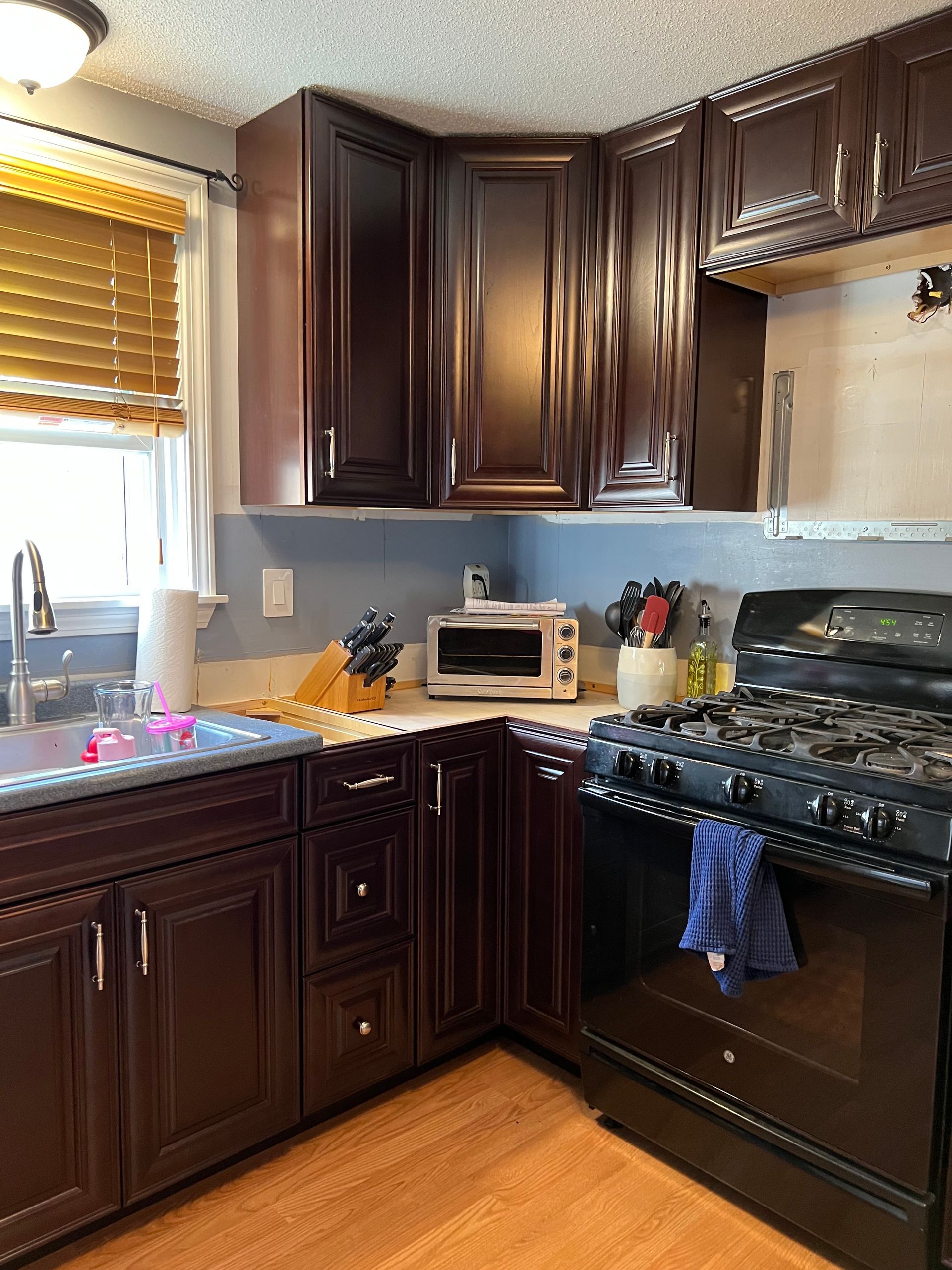 Dark wood kitchen with cabinets, stove, and small appliances.