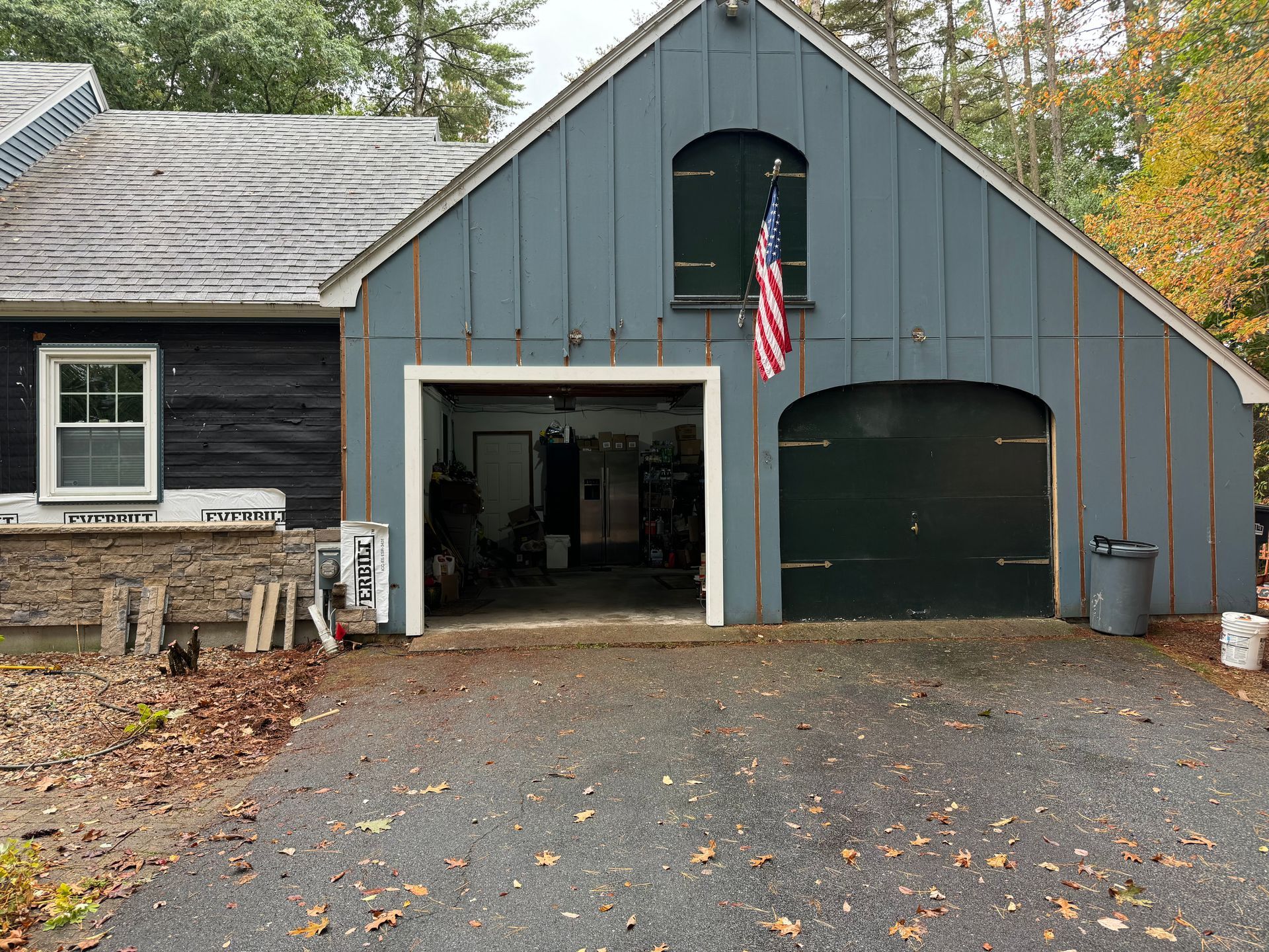Garage with blue siding and an open door, American flag hanging.