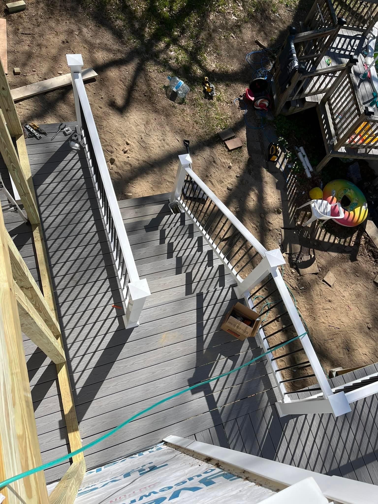 Overhead view of a deck with white railing and black spindles; backyard in sunlight.