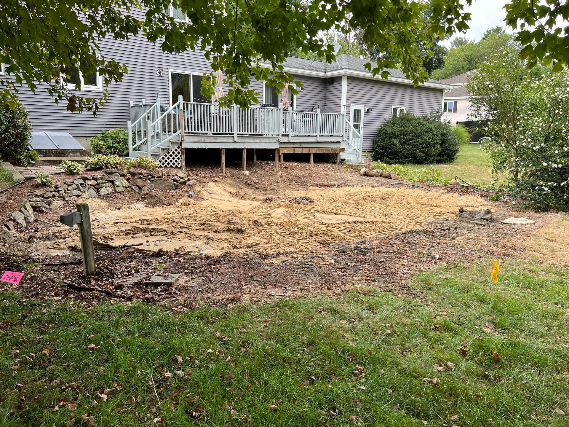 Backyard scene with house, deck, and cleared ground ready for landscaping.