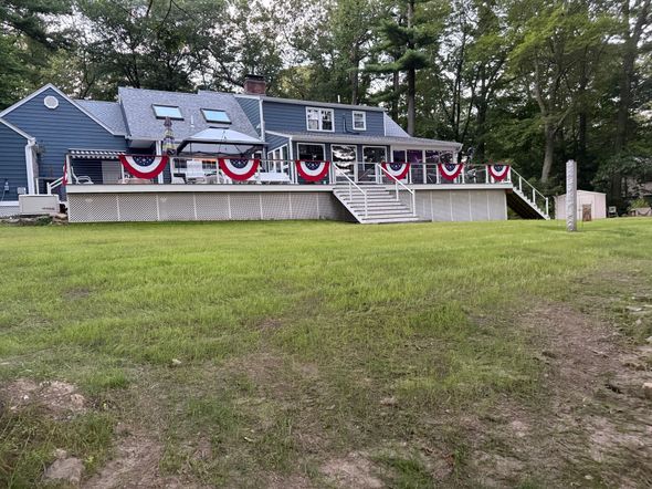 Empty above-ground pool with blue mosaic lining, next to a wooden deck with white railing.