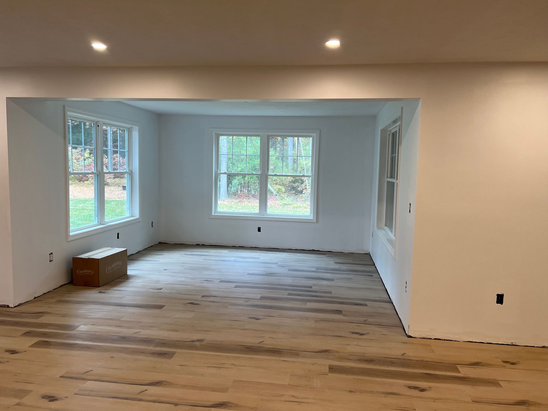 Empty room with hardwood floors, white walls, and windows, ready for decorating.