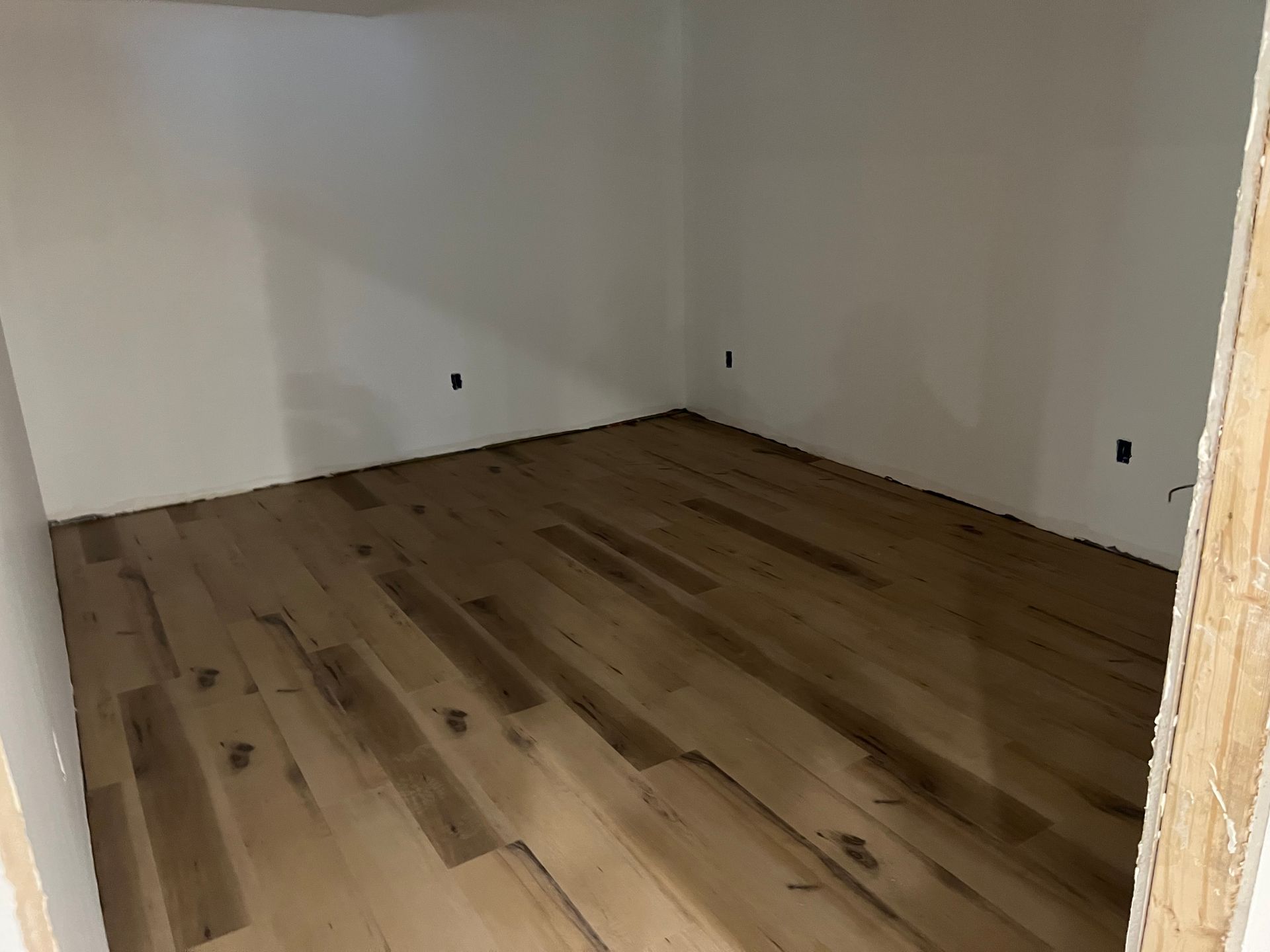Empty room with light wood floor and white walls.