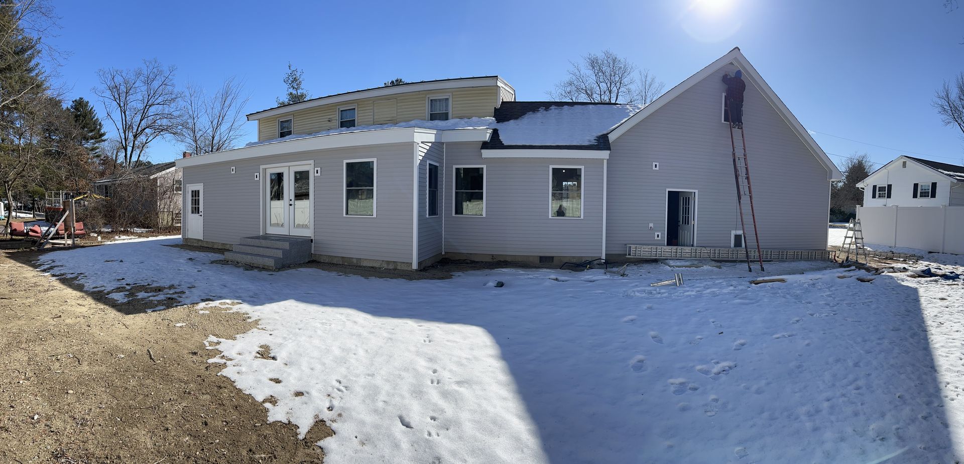 A house under construction on a snowy day, with a ladder against its side.