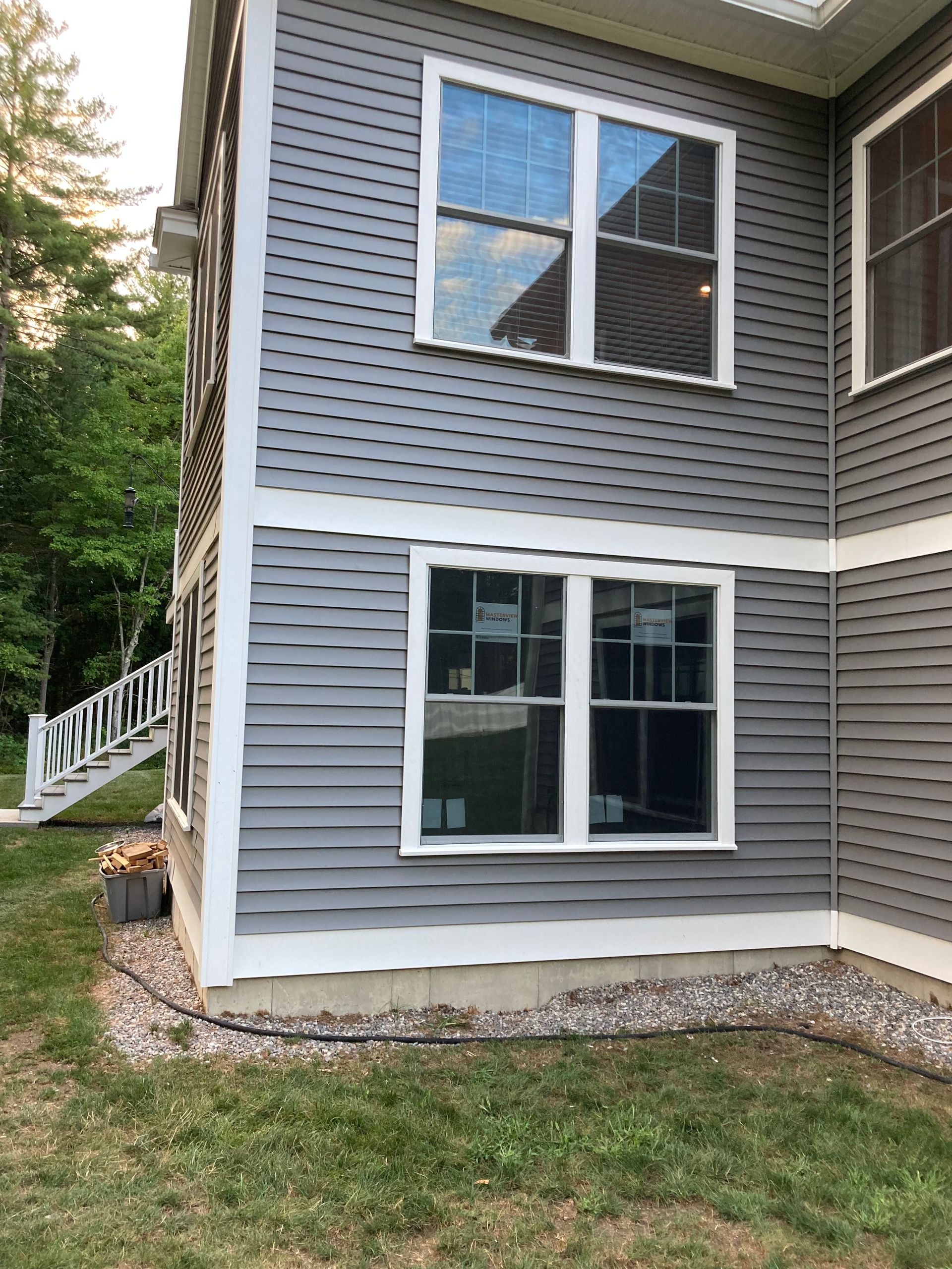 Gray house with white trim, two windows, and side stairs.