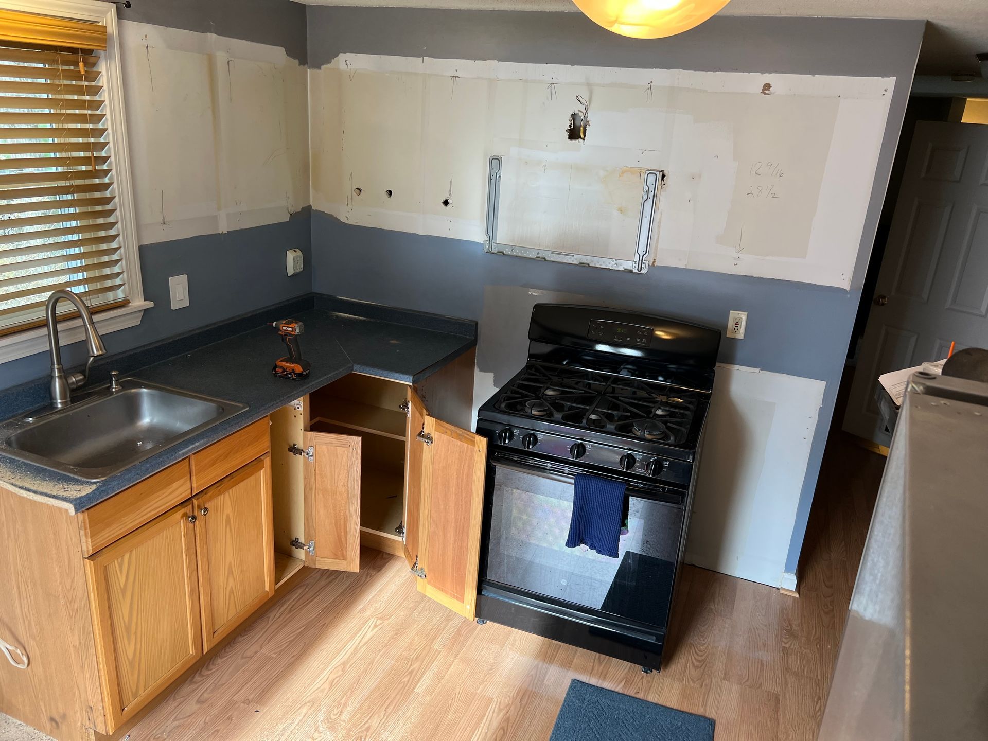 Kitchen remodel in progress with cabinets, stove, and partial drywall.