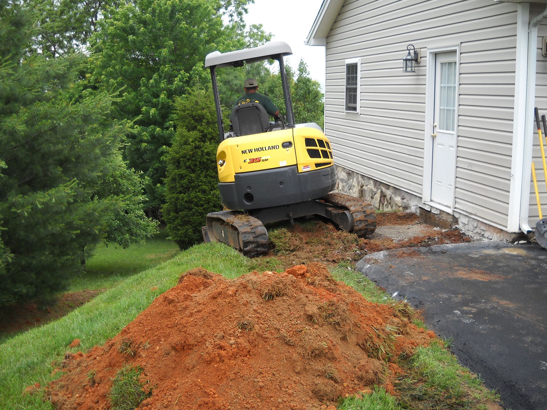 A yellow and black excavator is in front of a house