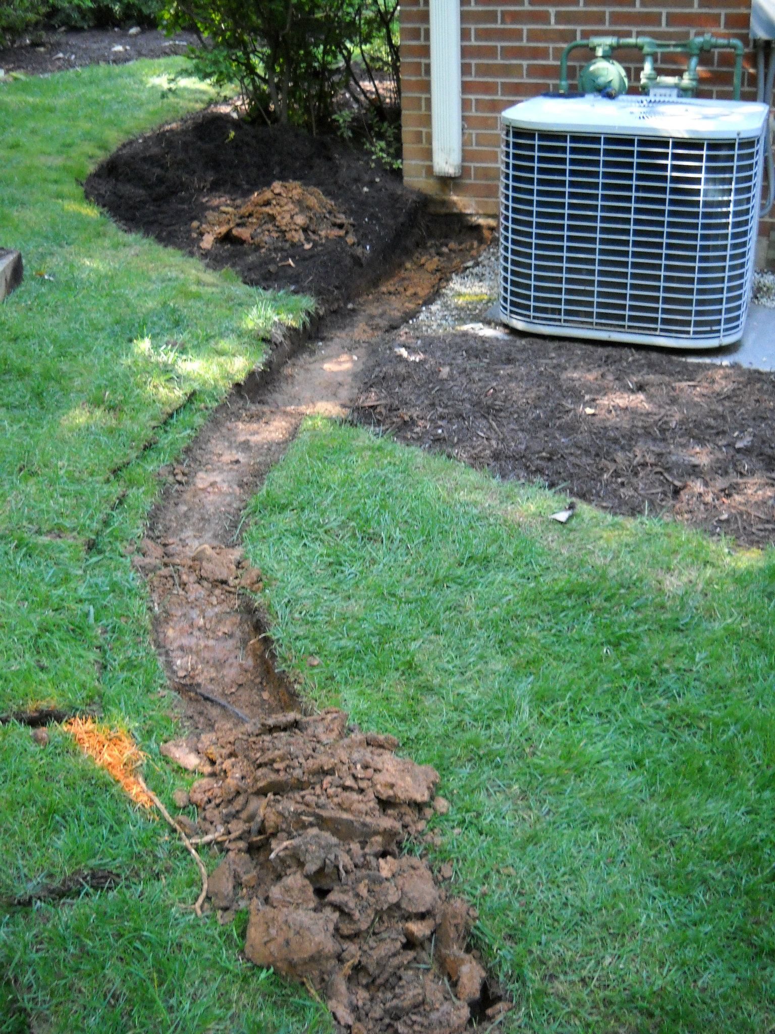 A drainage system is being installed in the backyard of a house.