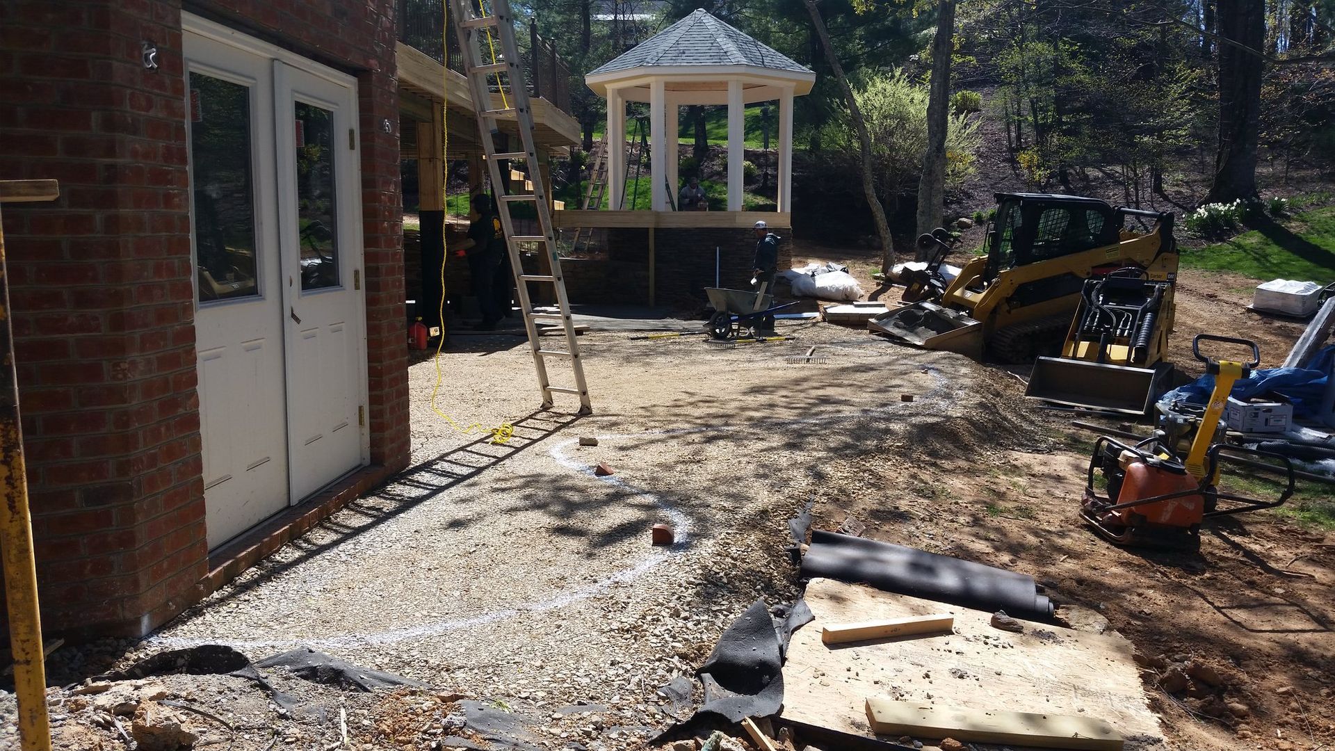 A construction site with a brick building and a gazebo in the background.