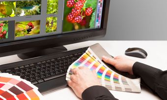 A person is holding a color palette in front of a computer