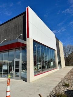 Modern storefront with large glass windows and a white-and-red facade under a blue sky