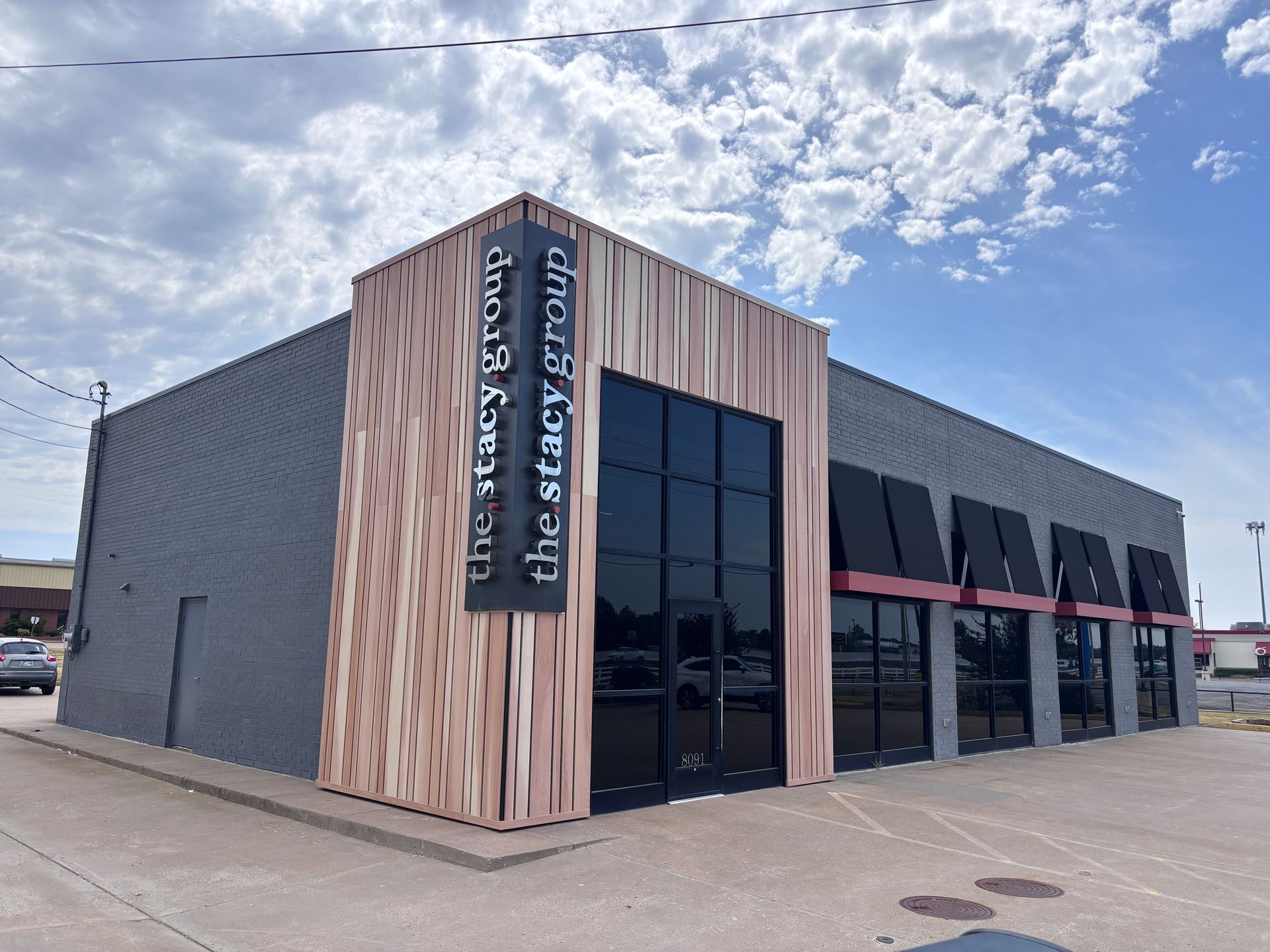 Modern commercial building with wood paneling and a sign reading “The Venue at…” under a cloudy sky