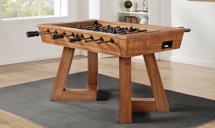 Wooden foosball table with black and brown figures, set on a wooden base.