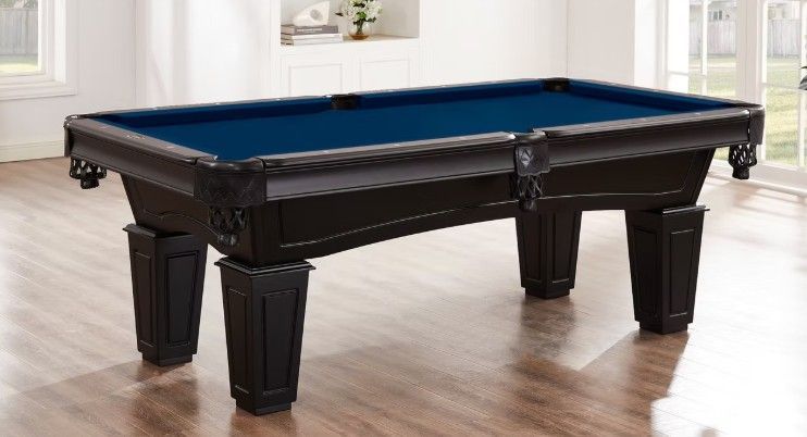 Black pool table with blue felt, in a brightly lit room.
