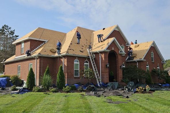 A group of people are working on the roof of a large brick house